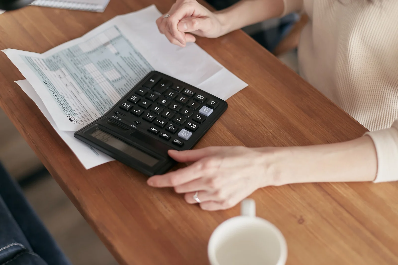 Finansal belgelerin yanında hesap makinesi kullanan eller